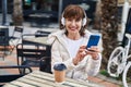 Middle age woman listening to music sitting on table at coffee shop terrace Royalty Free Stock Photo