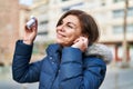 Middle age woman listening to music standing at street Royalty Free Stock Photo