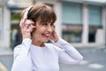 Middle age woman listening to music at street Royalty Free Stock Photo