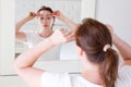 Middle age woman looking in mirror on face wrinkle forehead in bedroom. Wrinkles and anti aging skin care concept. Selective focus