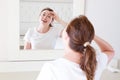 Middle age woman looking in mirror on face wrinkle forehead in bedroom. Wrinkles and anti aging skin care concept. Selective focus