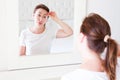 Middle age woman looking in mirror on face wrinkle forehead in bedroom. Wrinkles and anti aging skin care concept. Selective focus