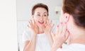 Middle age woman looking in mirror on face. Wrinkles and anti aging skin care concept. Selective focus. Banner Royalty Free Stock Photo
