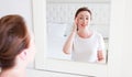 Middle age woman looking in mirror on face. Wrinkles and anti aging skin care concept. Selective focus Royalty Free Stock Photo