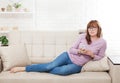 Middle age woman lying on sofa and using smartphone at home background. Copy space and mock up. Online shopping, internet Royalty Free Stock Photo