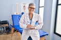 Middle age woman physiotherapist writing on clipboard at rehab clinic