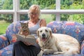 Middle age woman is reading a book with pets together Royalty Free Stock Photo