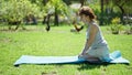 Middle age woman sitting on knees on yoga mat with serious face at park Royalty Free Stock Photo