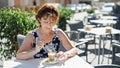 Middle age woman stir the coffee at coffee shop terrace Royalty Free Stock Photo