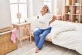 Middle age woman suffering for back pain sitting on bed at bedroom Royalty Free Stock Photo