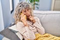 Middle age woman talking on the smartphone sitting on sofa at home Royalty Free Stock Photo