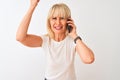 Middle age woman talking on the smartphone standing over isolated white background annoyed and frustrated shouting with anger, Royalty Free Stock Photo