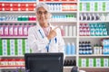 Middle age woman with tattoos working at pharmacy drugstore cheerful with a smile on face pointing with hand and finger up to the Royalty Free Stock Photo