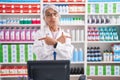 Middle age woman with tattoos working at pharmacy drugstore pointing to both sides with fingers, different direction disagree Royalty Free Stock Photo