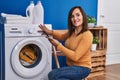 Middle age woman turning on washing machine using smartphone at laundry room Royalty Free Stock Photo