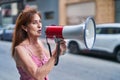 Middle age woman using megaphone speaking at street