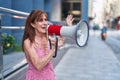 Middle age woman using megaphone speaking at street