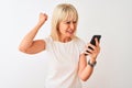 Middle age woman using smartphone standing over isolated white background annoyed and frustrated shouting with anger, crazy and Royalty Free Stock Photo