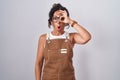 Middle age woman wearing apron over white background doing ok gesture shocked with surprised face, eye looking through fingers Royalty Free Stock Photo