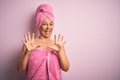 Middle age woman wearing bath towel from beauty body care over pink background afraid and terrified with fear expression stop