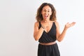 Middle age woman wearing black casual dress standing over isolated white background amazed and smiling to the camera while Royalty Free Stock Photo