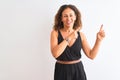 Middle age woman wearing black casual dress standing over isolated white background smiling and looking at the camera pointing Royalty Free Stock Photo