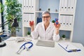 Middle age woman wearing doctor uniform holding heart ventricles at clinic