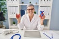 Middle age woman wearing doctor uniform holding heart ventricles at clinic