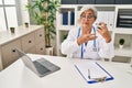 Middle age woman wearing doctor uniform holding inhaler at clinic Royalty Free Stock Photo