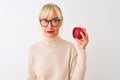 Middle age woman wearing glasses holding apple standing over isolated white background with a confident expression on smart face Royalty Free Stock Photo