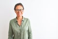 Middle age woman wearing green shirt and glasses standing over isolated white background with a happy and cool smile on face Royalty Free Stock Photo