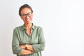 Middle age woman wearing green shirt and glasses standing over isolated white background happy face smiling with crossed arms Royalty Free Stock Photo