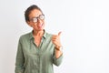 Middle age woman wearing green shirt and glasses standing over isolated white background smiling with happy face looking and Royalty Free Stock Photo