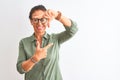 Middle age woman wearing green shirt and glasses standing over isolated white background smiling making frame with hands and Royalty Free Stock Photo