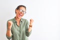 Middle age woman wearing green shirt and glasses standing over isolated white background very happy and excited doing winner Royalty Free Stock Photo