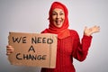 Middle age woman wearing muslim hijab asking for change holding banner very happy and excited, winner expression celebrating