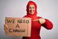 Middle age woman wearing muslim hijab asking for change holding banner very happy pointing with hand and finger