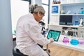 Middle age woman wearing scientist uniform watching embryo on touchpad at laboratory