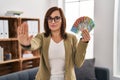 Middle age woman working at consultation office holding australian dollars with open hand doing stop sign with serious and Royalty Free Stock Photo