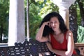 Middle-aged adult Hispanic woman with black curly hair, sitting on a park bench, angry. Concept anger, argument, problems, couple Royalty Free Stock Photo