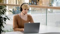 Middle aged adult 40s business woman in headset microphone talking at laptop web camera consultation online distant Royalty Free Stock Photo