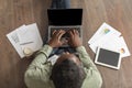 Middle aged african american man in glasses typing on laptop with empty screen sits on floor with graphs