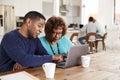 Middle aged African American man helping his mother use a laptop computer at home, close up