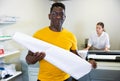 Middle-aged African American man holding large format paper whatman in a roll in the middle of the typography