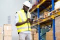 Middle aged African American warehouse worker preparing a shipment in large warehouse distribution centre Royalty Free Stock Photo