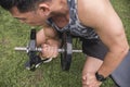 A middle aged asian guy exercising outdoors. Doing concentration bicep curls on a bench. Arm workout Royalty Free Stock Photo