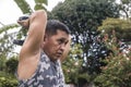 A middle aged asian man does dumbbell overhead triceps extension. Tricep workout done outdoors at the yard Royalty Free Stock Photo