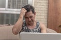 A middle aged asian man frustrated at a series he is watching on the laptop. A head-scratching twist or absurd and confusing plot