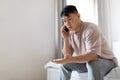 Middle aged asian man sitting on bed, have phone conversation Royalty Free Stock Photo