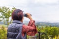 Middle aged asian tourist looking landscape view with binoculars